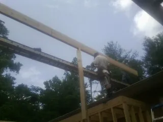 Carpenter setting a ridge beam over a new addition frame — Ice Dam Removal by Roofing Brothers in Concrete