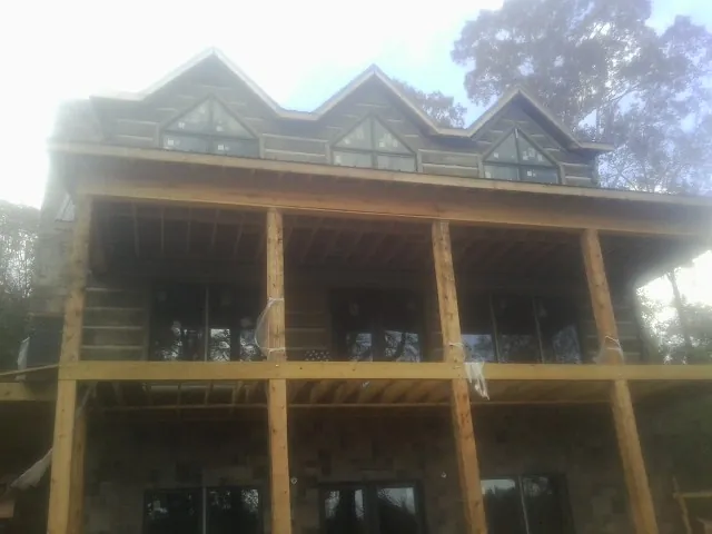 Dormers and porch framing on a large log home under construction — Roof Coating work by our crew in Concrete