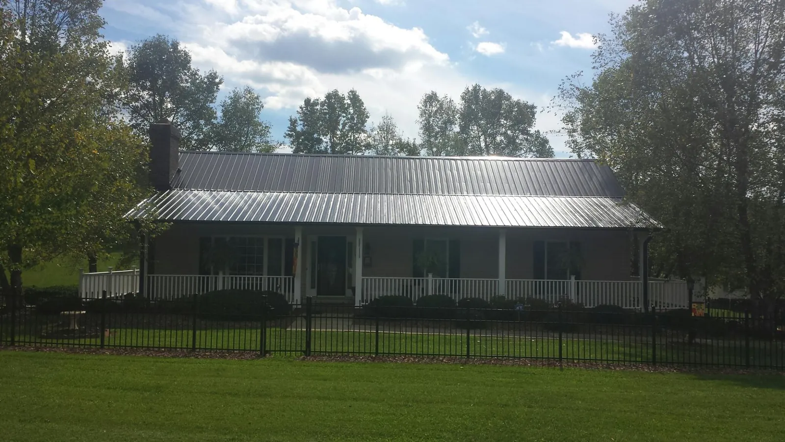 Gray metal roof on a brick ranch with a full width front porch — Gutter Guard Installation work by our crew in Concrete