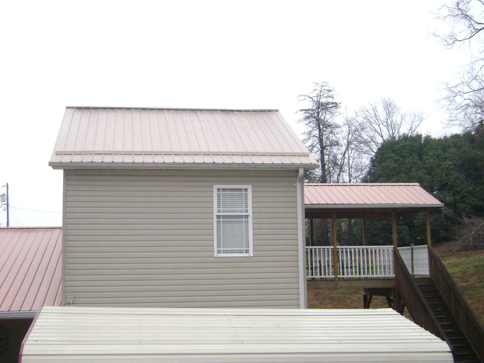 Tan metal roofs on a two story addition and attached porch, from a Roof Replacement job in Concrete