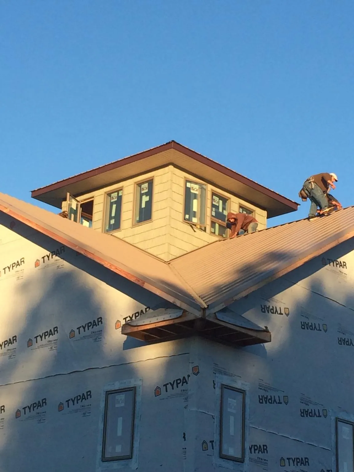 Roofers working around a rooftop cupola on a new metal roof at sunset — Roof Waterproofing in Concrete by Roofing Brothers
